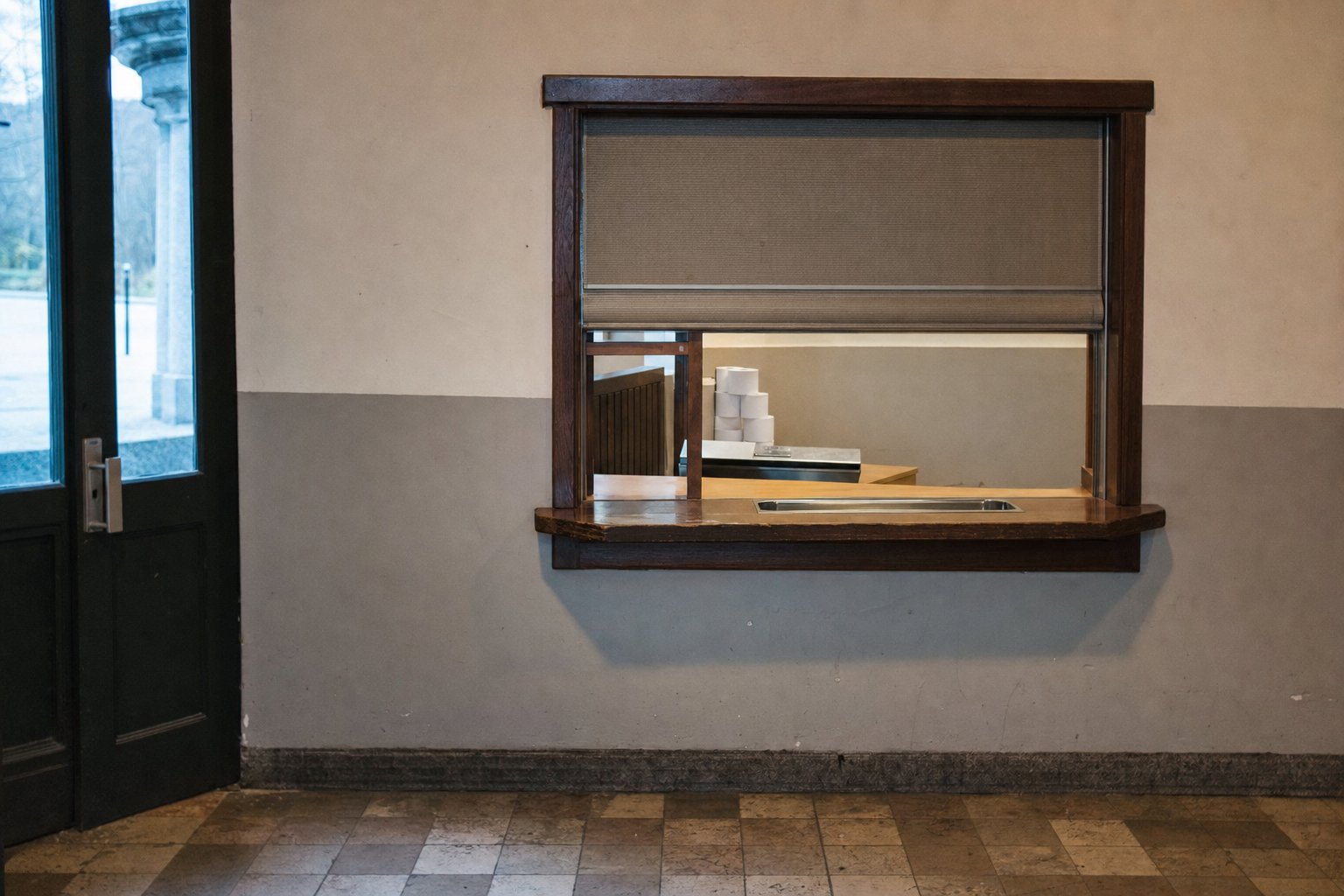 Guichet de billetterie fermé dans le foyer d’une salle, comptoir vide derrière la vitre