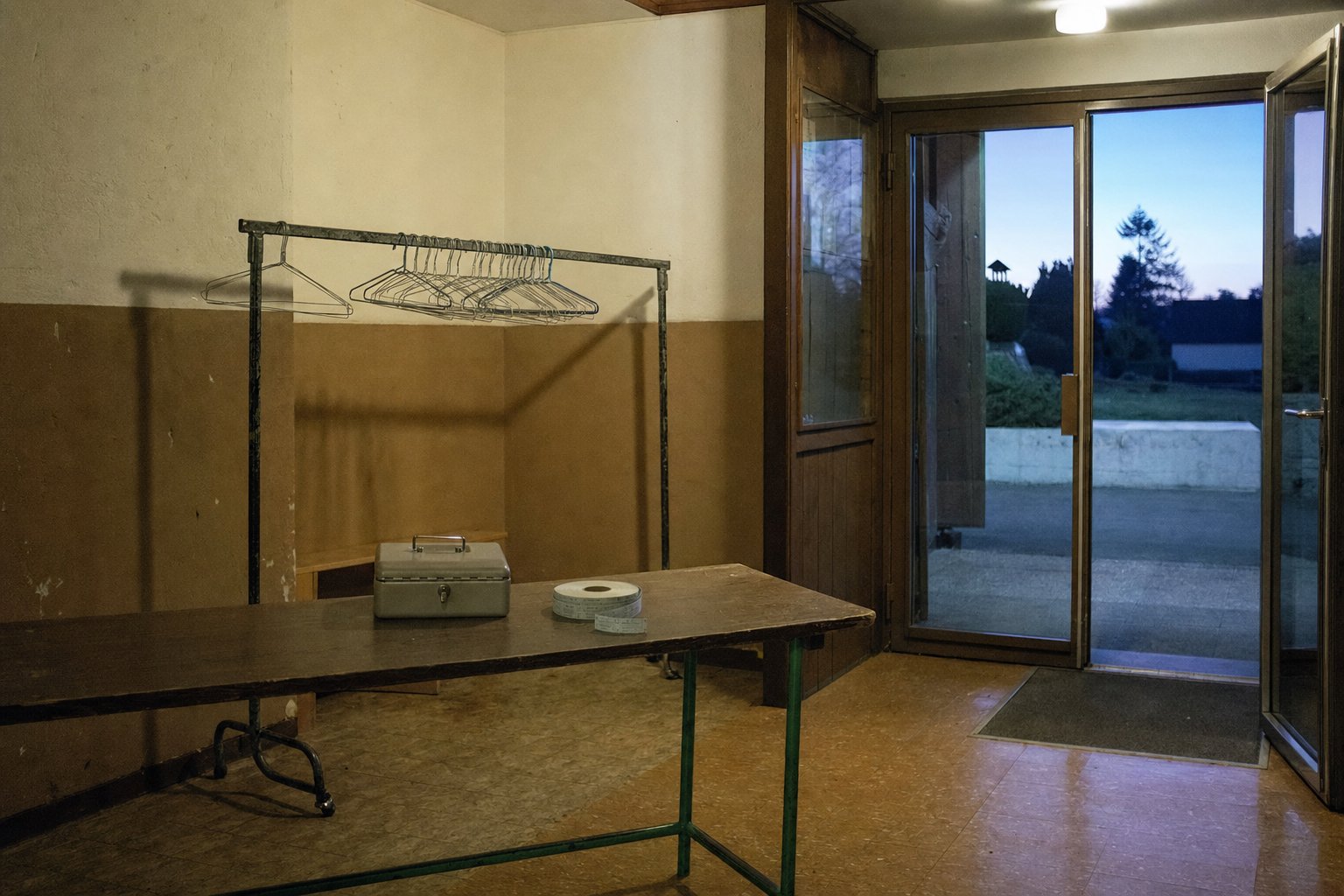 Hall d’entrée d’une salle communale avant l’ouverture des portes, table de caisse et portant à manteaux