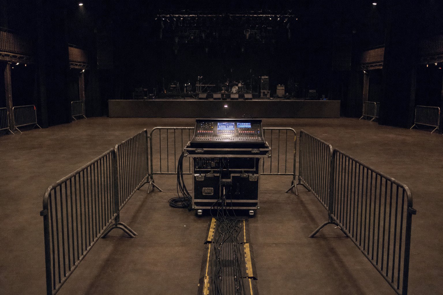 Régie son installée au milieu du sol d’une salle de concert, entourée de barrières
